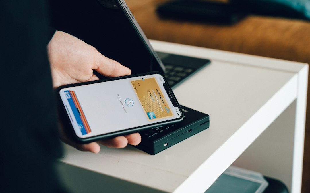 Payment card held beside a smartphone, illustrating account-name and payment-method checks.